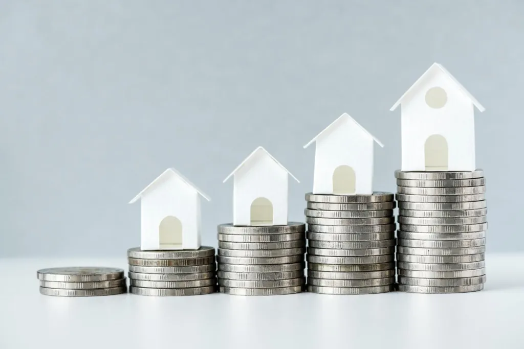 Indonesia Real Estate Investment Opportunities: Increasing stacks of coins with small white house models on top, representing the concept of real estate investment and growth.