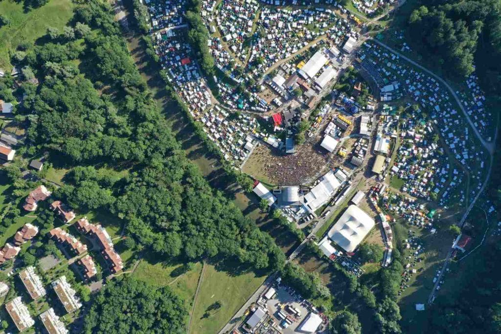 Vietnam Urban Renewal Initiatives: Aerial view of a vibrant festival crowded with tents and stages, surrounded by trees and residential buildings.