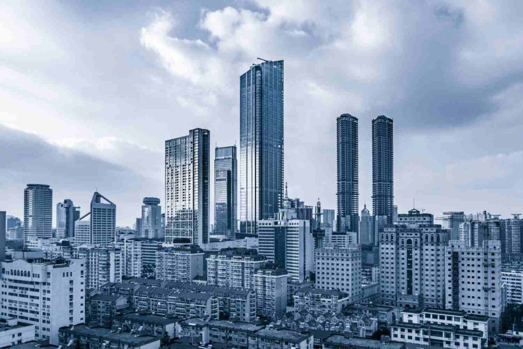 Indonesia Real Estate Investment Opportunities: A panoramic view of a modern city skyline featuring tall skyscrapers under a cloudy sky, blending contemporary architecture with older buildings.