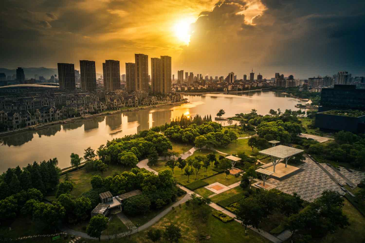 Vietnam Real Estate Investment Opportunities: Sunset over a scenic urban landscape, featuring modern skyscrapers, lush greenery, and a tranquil river reflecting the golden sky.