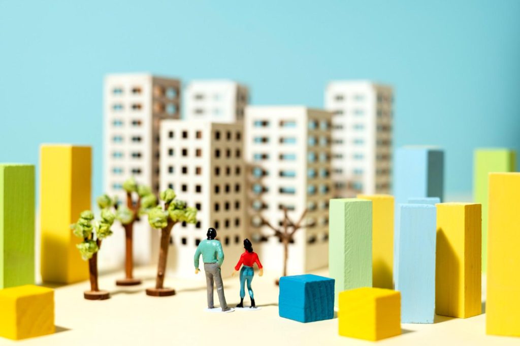 Philippines Real Estate Market Dynamics: A miniature scene depicting a couple standing in front of colorful buildings and trees, exploring a vibrant urban landscape.