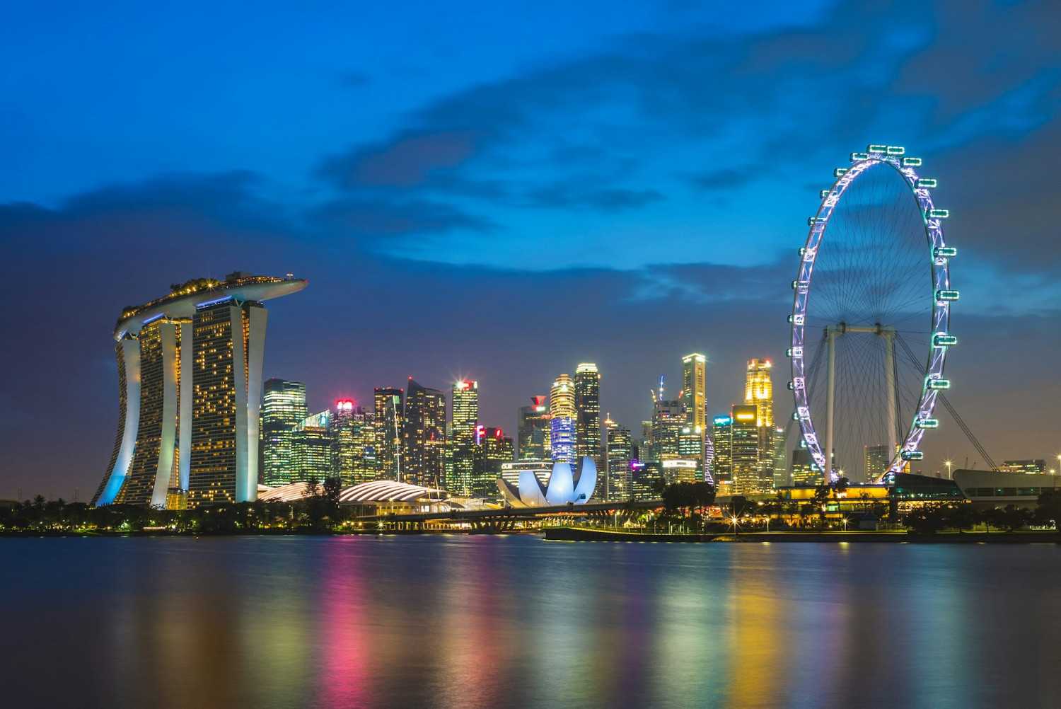 Singapore Real Estate Market Insights: The skyline of Singapore at twilight, featuring the Marina Bay Sands, a lotus-shaped building, and the iconic Ferris wheel.