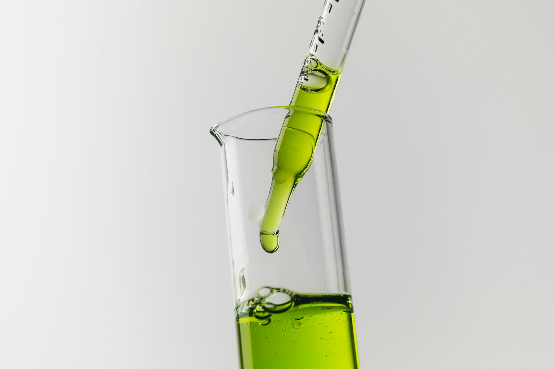 Green ammonia export MEA: A glass beaker contains vibrant green liquid, while a dropper releases more of the liquid into it.